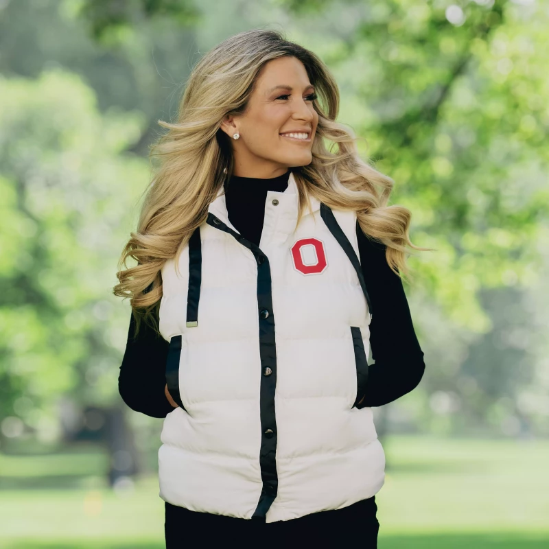 A model wears a white Ohio State puffer vest on top of a black long sleeve and black jeans.